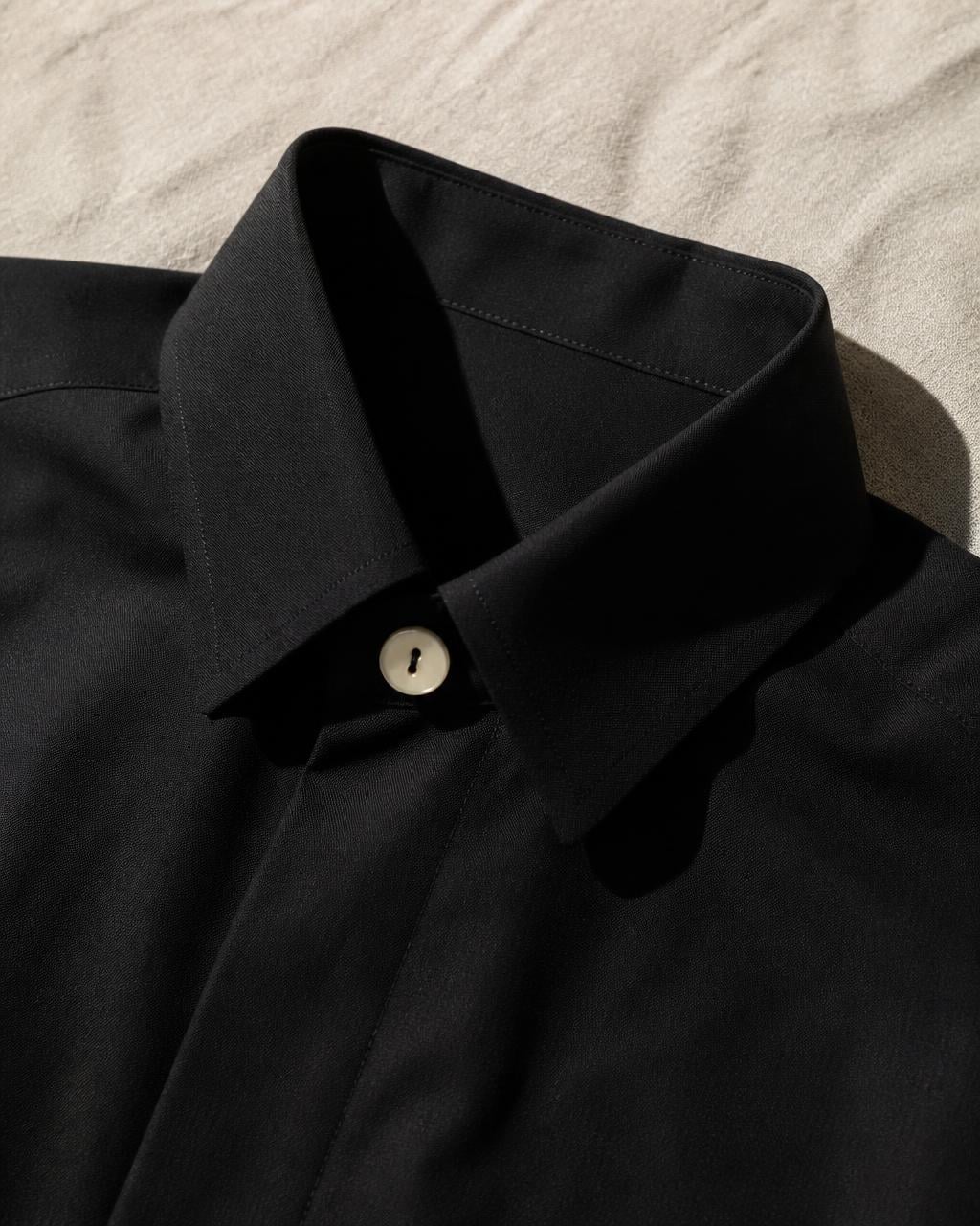 Collar and button of a black tailored shirt on raw linen