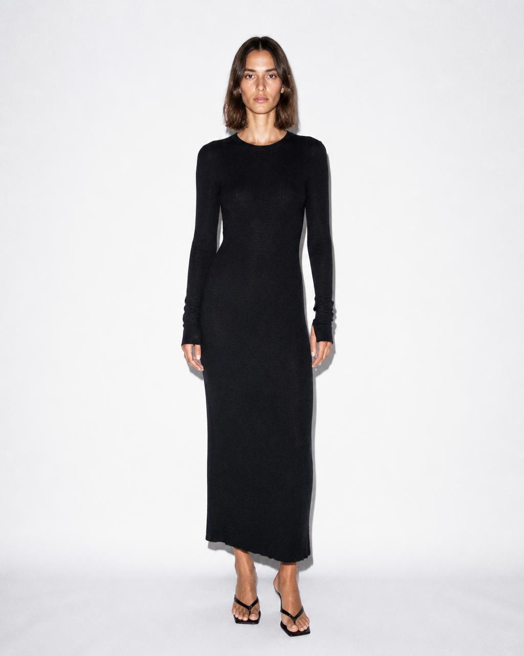 Slim model in a long black knit dress on a white studio background